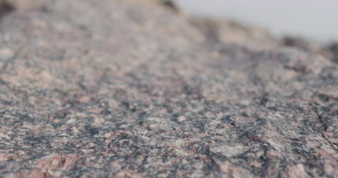 Handheld closeup slide over big granite rock