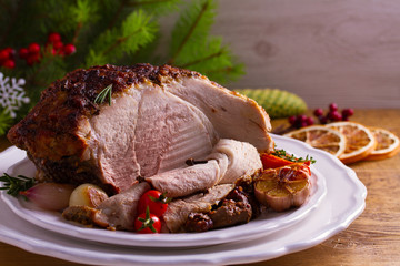 Baked ham with vegetables: carrots, onions, tomatoes, garlic and herbs. Christmas decorations. Dish...