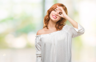 Young beautiful woman over isolated background doing ok gesture with hand smiling, eye looking through fingers with happy face.