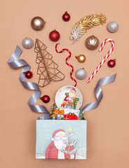 Christmas and New Year flat lay. Top view of a holiday gift, a box with Christmas toys, ribbons, candy, Christmas tree, balls. Festive mood with space for text