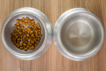 dry dog food in bowl on wooden background top view
