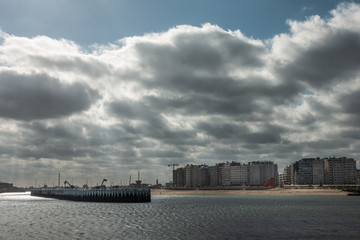 Naklejka premium Oostende, Flanders, Belgium - September 18, 2018: Heavy cloudscape over wall of condominium buildings along beach, often called Atlantic Wall. Old Staketsel on the left. Shot from Western sea barrier.