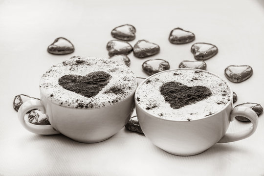 Two cup of coffee with heart symbol and candy around. Image in black and white color style