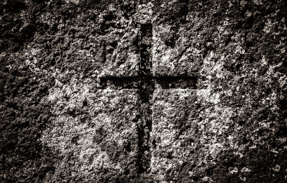 christian cross on an old shattered and cracked grave in an old cemetery in Europe. Image in black and white color style
