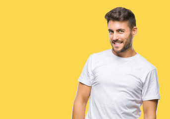 Fototapeta premium Young handsome man over isolated background looking away to side with smile on face, natural expression. Laughing confident.