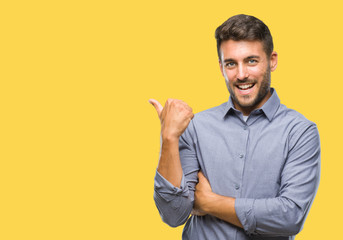 Young handsome man over isolated background smiling with happy face looking and pointing to the side with thumb up.