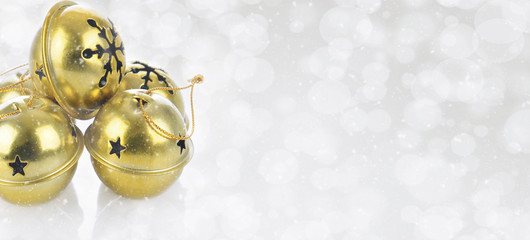 Gold Jingle bells on a snowy bokeh silver background
