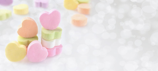Pastel Candy hearts on a silver bokeh background