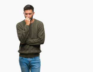 Adult hispanic man wearing winter sweater over isolated background looking stressed and nervous with hands on mouth biting nails. Anxiety problem.