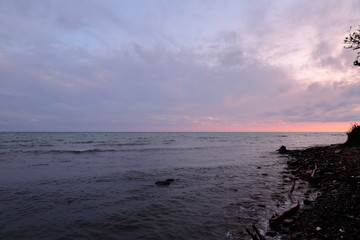 Obraz premium Sunset, the sun's rays make their way through the heavy clouds and illuminate the summer, troubled sea