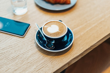 Obraz premium Close up of coffee cup on wooden table in cafe. Concept of tasty breakfast.