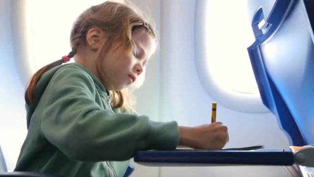 Little girl drawing in the airplane