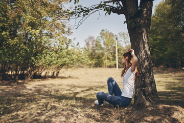 woman jeans sitting on the ground near a tree