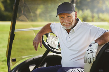 Senior man smiling while sitting in a golf cart