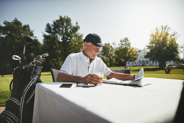 Senior man relaxing with coffee at his golf clubhouse - obrazy, fototapety, plakaty
