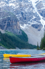 Fototapeta na wymiar Red and yellow canoes on Moraine Lake in Banff National Park, Canada