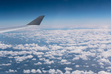An airbus wing while flying over some clouds.