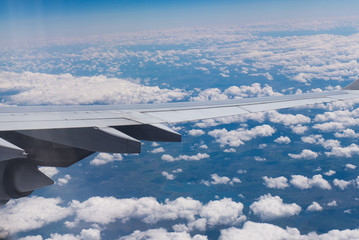 An airbus wing while flying over some clouds.