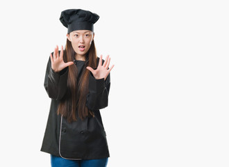 Young Chinese woman over isolated background wearing chef uniform afraid and terrified with fear expression stop gesture with hands, shouting in shock. Panic concept.