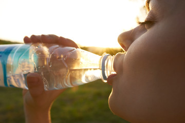 woman drinking water from a bottle in nature