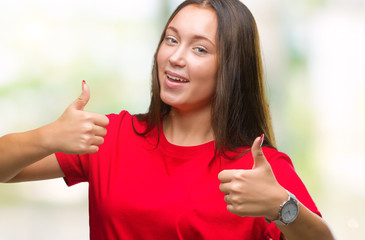 Young beautiful caucasian woman over isolated background approving doing positive gesture with hand, thumbs up smiling and happy for success. Looking at the camera, winner gesture.