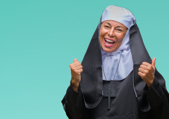 Middle age senior christian catholic nun woman over isolated background very happy and excited doing winner gesture with arms raised, smiling and screaming for success. Celebration concept.