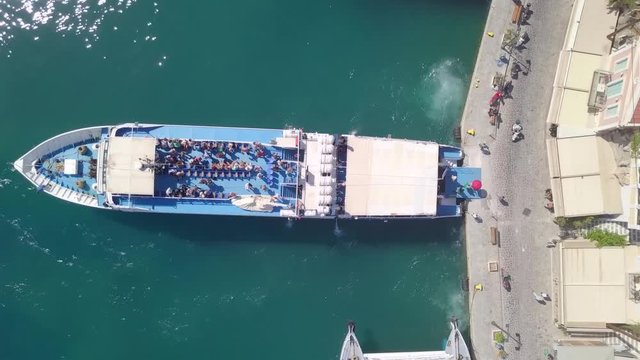 People leaving a medium sized passenger ferry docked at a Greek island port - Top down aerial footage.