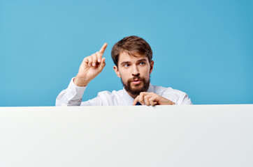 man stands behind white mockup poster on blue background