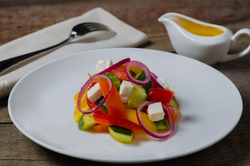 Village salad Horiatiki made with slices of tomatoes, peppers, sliced cucumbers, onion and feta cheese. 