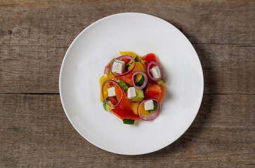 Village salad Horiatiki made with slices of tomatoes, peppers, sliced cucumbers, onion and feta cheese. The view from the top. Copy-space.