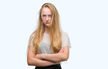 Blonde teenager woman wearing moles shirt skeptic and nervous, disapproving expression on face with...