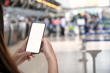 Cropped shot of female hand holding mobile phone in airport terminal