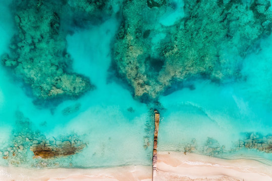 Top Aerial View Of The Beach With Pier And Clear Caribbean Ocean Water, Coral Reefs. Summer Background