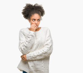 Fototapeta na wymiar Young afro american woman wearing winter sweater over isolated background looking stressed and nervous with hands on mouth biting nails. Anxiety problem.