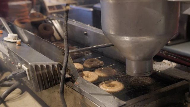 An automatic machine making fresh apple cider donuts ready to eat.