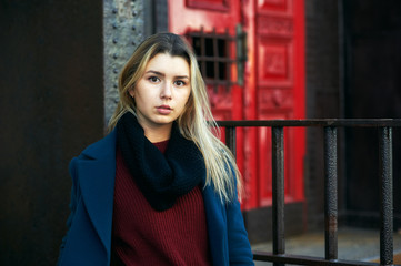 Portrait of a young girl in the autumn city . The girl in warm and comfortable clothes
