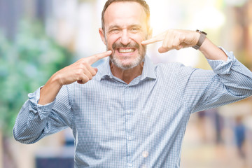 Middle age hoary senior business man over isolated background smiling confident showing and pointing with fingers teeth and mouth. Health concept.