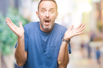 Middle age hoary senior man over isolated background clueless and confused expression with arms and...