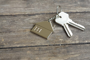 House keys with wooden home keying on wood table, copy space, property concept