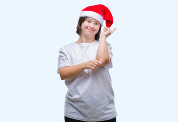 Obraz premium Young adult woman with down syndrome wearing christmas hat over isolated background with a big smile on face, pointing with hand and finger to the side looking at the camera.