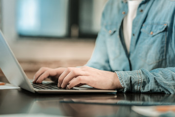 Professional freelancer. Close up of a nice smart handsome man typing on the keyboard while working at the laptop