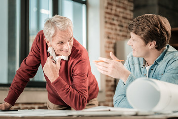 Smart engineer. Happy nice positive colleagues smiling and talking together while working on an eco...