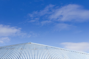 Fototapeta na wymiar Blue tin corrugated tin roof with blue sky in the background. Sunny day.