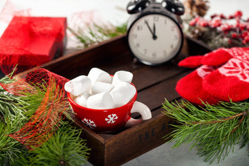 Christmas card. Fir tree, mittens, box, alarm clock and  marshmallow on wooden table. Selective focus