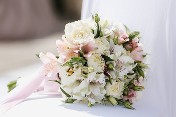 The bridal bouquet lies on the surface and consists of lilies, roses, peonies, lumpy roses, peony roses