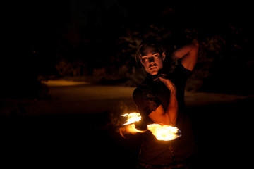 Fire show. Fakir juggles with fire Poi. Night performance. Dramatic portrait.