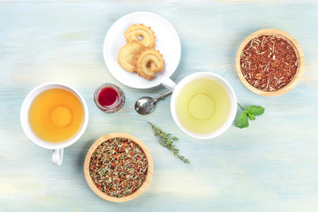 Tea tasting. Various cups of tea and loose dry tea leaves with cookies, jam, and copy space