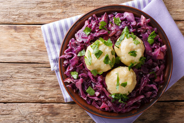 German food knodel potato dumplings and stewed red cabbage close-up on a plate. Horizontal top view...