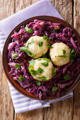 Freshly cooked potato dumplings served with stewed red cabbage close-up on a plate. Vertical top...