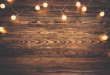 Old wooden planks with christmas decoration. Brown background with lightbulbs